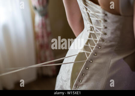 Braut von hinten. Schnürung das Hochzeitskleid. Stockfoto