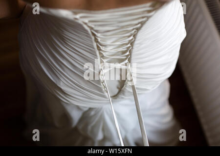 Braut von hinten. Schnürung das Hochzeitskleid. Stockfoto