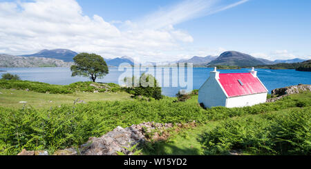 Weißes Häuschen mit rotem Dach auf Loch Sheildaig Blick über auf die Berge von torridon an der Nordküste 500 Route, Highland, Westküste, Schottland Stockfoto