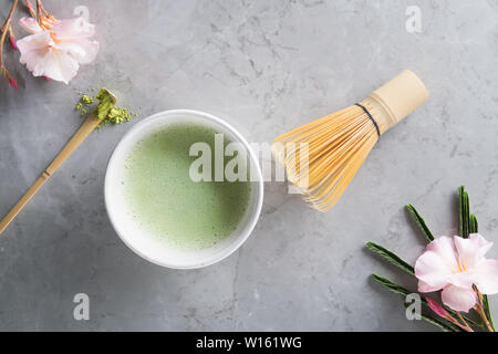Blick von oben auf die grünen Tee Matcha Latte mit Bambus chasen in einer Schüssel auf grauem Marmor mit schönen oleander Blumen. Japanische Teezeremonie Konzept, Kopieren sp Stockfoto