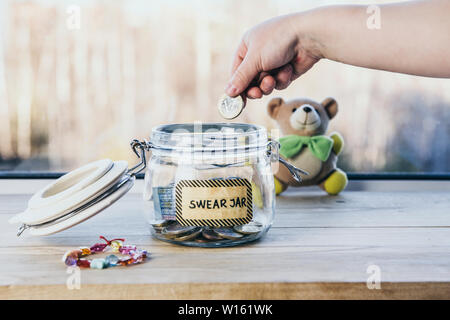 Selektiver Fokus auf Kind Hand, Euro Münze in jar schwören. Jedem Kind Flüche oder schwört er hat Geld zu setzen, als Strafe in Jar für sicher hält. Stockfoto