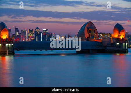 LONDON, UK - 29. JUNI 2019: Nacht Blick auf Canary Wharf, einem der wichtigsten Finanzzentren der VEREINIGTEN KÖNIGREICH über den Fluss Themse, und Thames Barrier, der Welt Stockfoto