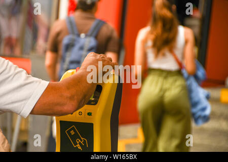 COMO, ITALIEN - JUNI 2019: Person Validierung ein Ticket in eine Maschine in der Talstation der Standseilbahn in Como am Comer See. Stockfoto