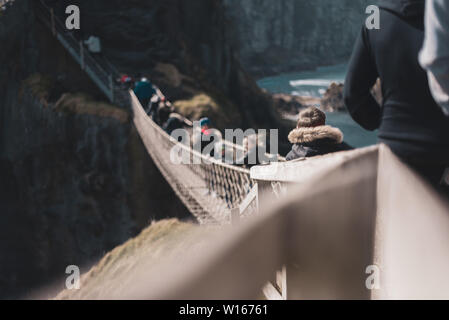 Nordirland, Großbritannien - 8 April 2019: Angst Touristen der gefährlichen, aber wunderschönen Carrick-a-Rede Rope Bridge überqueren Stockfoto