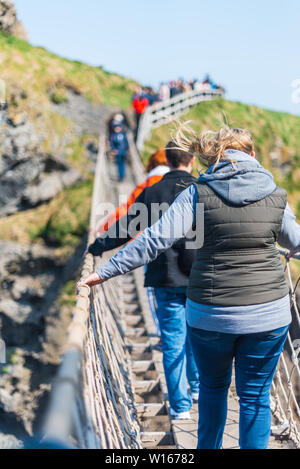 Nordirland, Großbritannien - 8 April 2019: Angst Touristen der gefährlichen, aber wunderschönen Carrick-a-Rede Rope Bridge überqueren Stockfoto