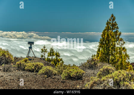 Berge und Kiefernwald in der Nähe von Vulkan Teide, teilweise durch die Wolken bedeckt. Strahlend blauen Himmel. Teleskop auf dem Stativ bereit, Beobachtung der Sonne. 10 Stockfoto