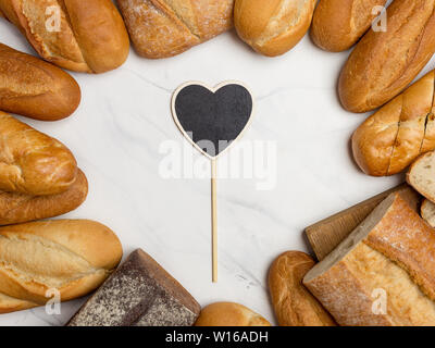 Brot am Rand auf weißem Hintergrund mit Herzen am Zentrum für Ihren Text. Flach, horizontale Ansicht von oben Stockfoto