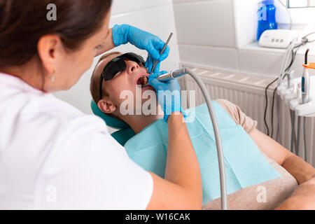 Zahnheilkunde, Zahnarzt behandelt einen Zahn zu einem männlichen Patienten. Entfernen von Karies, die Installation von Füllungen auf den Zähnen. Stockfoto