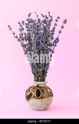 Fragrant Bouquet von trockenen Lavendel mit kleinen violetten Blüten in eine schöne Keramik Vase auf einem Pastell rosa Hintergrund. Aromatherapie und Komfort. Vor vi Stockfoto