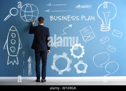 Mann in formelle Kleidung Zeichnung auf Farbe Wand. Konzept der Business Plan Entwicklung Stockfoto