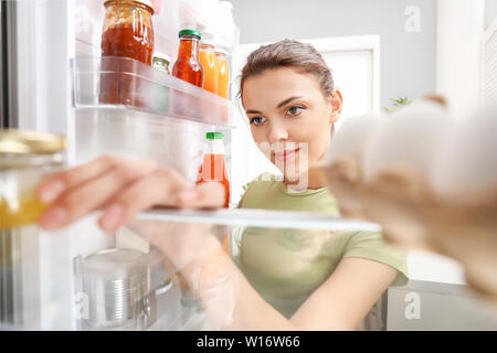 Frau Essen aus dem Kühlschrank zu Hause, Ansicht von innen Stockfoto