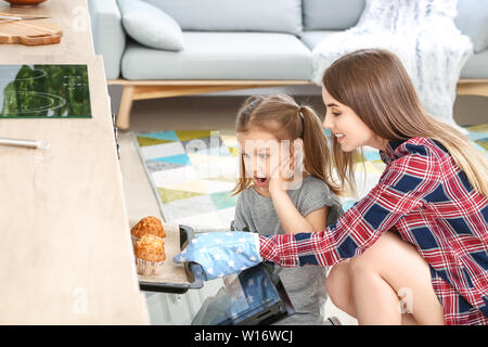 Junge Frau und ihre kleine Tochter Backen leckere Muffins zu Hause Stockfoto