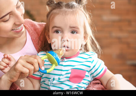 Die Mutter, die ihre kleine Tochter nibbler mit leckerem Essen zu Hause Stockfoto