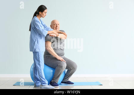 Jungen asiatischen Physiotherapeuten arbeiten mit älteren Menschen in der Klinik Stockfoto