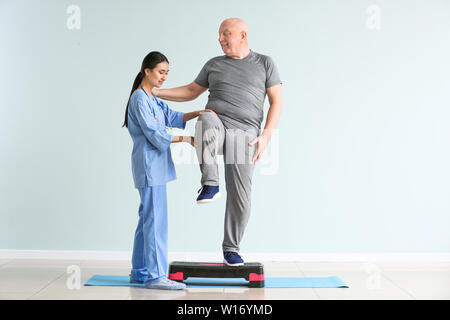 Jungen asiatischen Physiotherapeuten arbeiten mit älteren Menschen in der Klinik Stockfoto