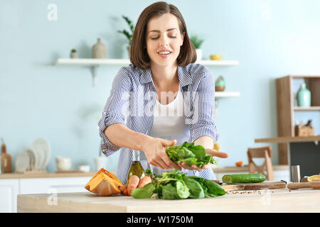 Junge Frau, Salat in der Küche Stockfoto