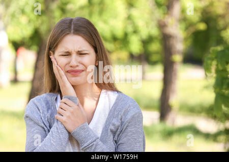 Junge Frau mit Zahnschmerzen im Freien Stockfoto