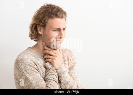 Junge Menschen leiden unter Halsschmerzen auf weißem Hintergrund Stockfoto