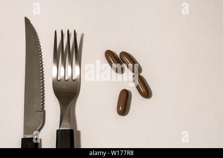 Kapseln, Pillen, Messer und Gabel, als wäre es das Essen der Zukunft. Stockfoto