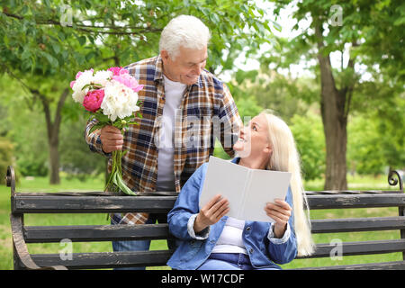 Reife Frau Blumen von ihrem Ehemann in Park Stockfoto