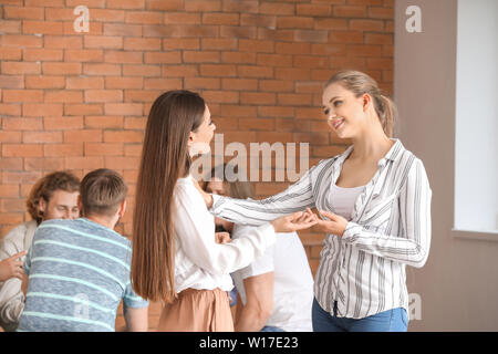 Junge Frau beruhigt ihren Freund an der Gruppe Therapie Sitzung Stockfoto