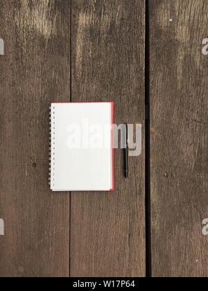 Seite "Notizbuch" und schwarzen Stift auf alten Holztisch Hintergrund mit kopieren. Leere Notepad öffnen Blatt auf einem dunklen Holz- Oberfläche. Ansicht von oben Hinweis öffnen Boo Stockfoto