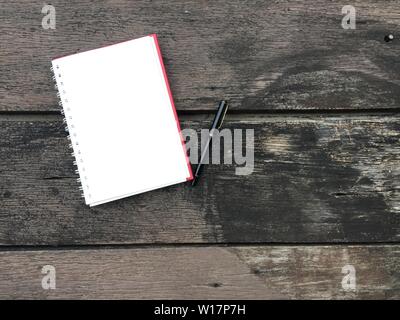 Seite "Notizbuch" und schwarzen Stift auf alten Holztisch Hintergrund mit kopieren. Leere Notepad öffnen Blatt auf einem dunklen Holz- Oberfläche. Ansicht von oben Hinweis öffnen Boo Stockfoto