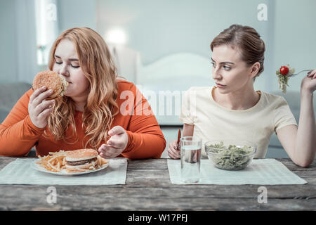 Rätselhafte Übergewicht weibliche Person riechen leckere Burger Stockfoto