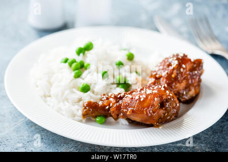 Hähnchenschenkel mit Reis und Sesam auf weiße Platte. Gesundes Abendessen Stockfoto