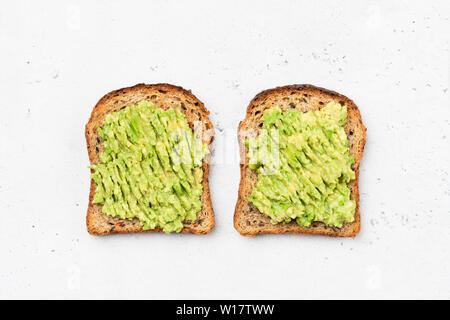 Avocado Toast auf Vollkorn sandwich Brot. Tabelle Ansicht von oben. Guacamole Toasts. Konzept der gesunden Ernährung, Diäten, vegan vegetarische Kost Stockfoto