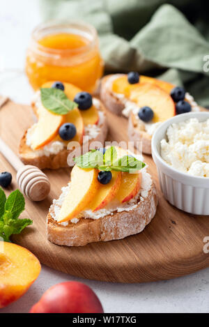 Vorspeise Bruschetta mit Ricotta Käse, Früchten und Honig auf Holz serviert. Detailansicht, selektiver Fokus Stockfoto