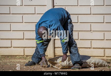 Johannesburg, Südafrika - ein unbekannter Mann in Schwarz funktioniert die manuelle Arbeit im heimischen Garten in der Stadt Bild im Querformat. Stockfoto