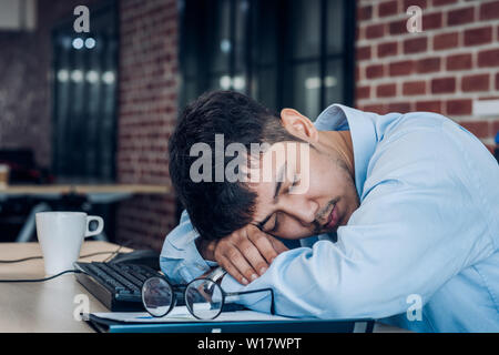 Müde asiatische Geschäftsmann schlafen auf Schreibtisch Tisch im Amt. arbeiten hart und spät Stockfoto