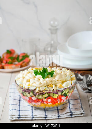 Große Glasschüssel mit Krabben Salat, Mais, Gurken und Reis auf dem Tisch. 2-in-1-Crab Sticks und Feldsalat. Traditiolnal mayonnaise Salat für russische Urlaub fest, einschließlich für das neue Jahr. Vertikale. Platz kopieren Stockfoto