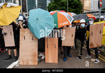 Anti Regierung Demonstranten mit Sonnenschirmen und Holz- hausgemachte schirmt sich von der Polizei während der distanzhülse zu schützen. Tausende von Demonstranten gegen die Regierung stellte weg mit Bereitschaftspolizei und Straßen rund um die Regierung von Hongkong Komplexe in der 22. Jahrestag der Rückkehr Hongkongs unter chinesische Herrschaft besetzen. Stockfoto