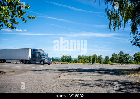 Big Rig Dunkelgrau professionelle industrielle Motorhaube Long Haul Semi Truck mit trockenen van Auflieger für den Transport von verpackten kommerziellen Ladung steht i Stockfoto