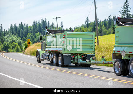 Big Rig leistungsstarke Industrie braun Kipper semi Traktor mit zwei dump Trailer für schwere Lasten, die auf den kurvenreichen Straße in grüne Bäume Wald wi Tuck Stockfoto