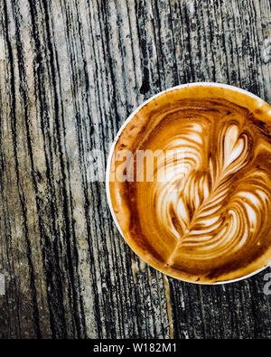 Tasse Kaffee Latte auf dunklem Holz Tisch, schöne Latte Art Stockfoto