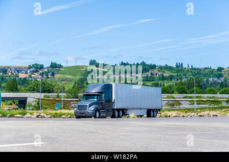 Big Rig Dunkelgrau professionelle industrielle Motorhaube Long Haul Semi Truck mit trockenen van Auflieger für den Transport von verpackten kommerziellen Ladung steht i Stockfoto