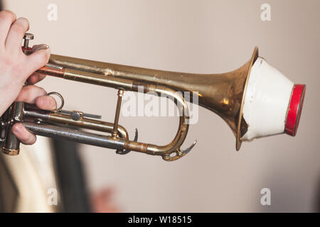 Live Musik im Hintergrund. Trompete mit geraden Mute in trompeter Hände. Stockfoto