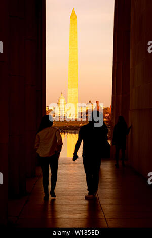 Das Washington Monument und dem Kapitol Kuppel bei Sonnenuntergang mit der Silhouette von Touristen, die das Lincoln Memorial Stockfoto