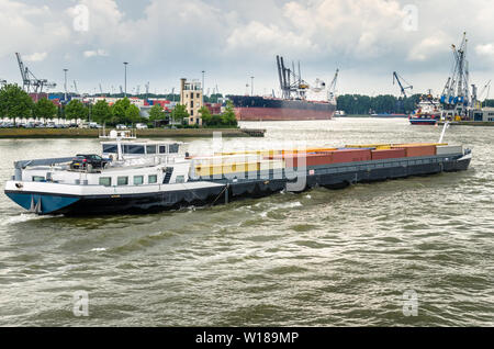 Blick auf einen Container barge in der Navigation in einem Hafen und bewölkter Himmel Stockfoto