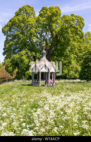 Maytime in den Cotswolds - Zwei weibliche Radfahrer in der 1874 Pumpenhaus vor der schönen alten Bergahorn Baum auf dem Dorfplatz in Farmington UK Stockfoto