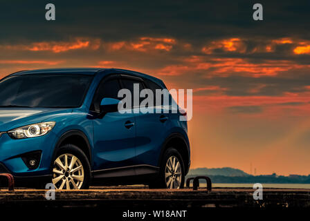 Blaue kompakte SUV-Auto mit Sport und modernes Design auf konkrete Straße geparkt am Strand bei Sonnenuntergang. Hybrid- und Elektroautos. Parkplatz. Stockfoto