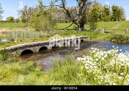 Eine alte Steinbrücke über den Sherborne Bach in der Nähe von Cotswold Village von Sherborne, Gloucestershire, Großbritannien Stockfoto