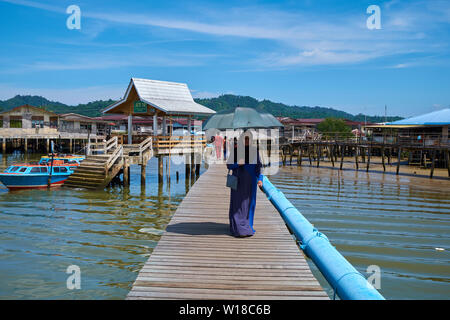 Menschen wallking entlang einer der wichtigsten Holz Wege ins Wasser stelze Dorf Kampong Ayer in Bandar Seri Begawan, Brunei. Stockfoto