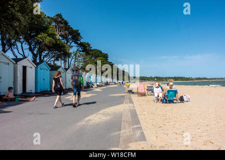 Avon Strand bei Mudeford, Christchurch, Dorset, Großbritannien. Einen Sandstrand mit Strandhütten Verkleidung oben am Strand. Leute sitzen in Liegestühlen auf dem Sand. Stockfoto