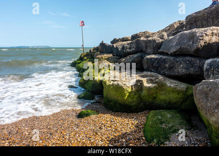 Eine groyne der grosse Felsbrocken auf Avon Strand bei Mudeford, Christchurch, Dorset, Großbritannien mit blauen Himmel an einem heißen, sonnigen, sommerlichen Tag, Stockfoto