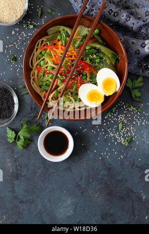 Nudeln mit Gemüse und Eier in der Schale auf dunklem Hintergrund. Ansicht von oben mit der Kopie. Asiatische Küche. Stockfoto