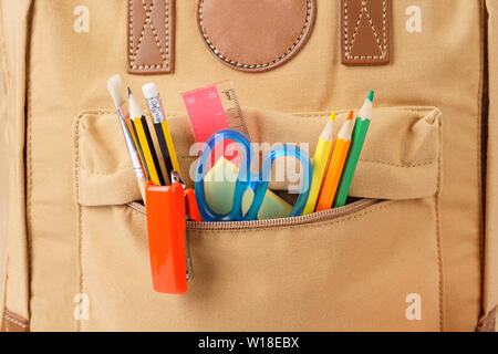 Braun Schule Rucksack mit verschiedenen bunten Schreibwaren und Zubehör - Stifte, Schere, Lineal Hefter. Nahaufnahme. Stockfoto